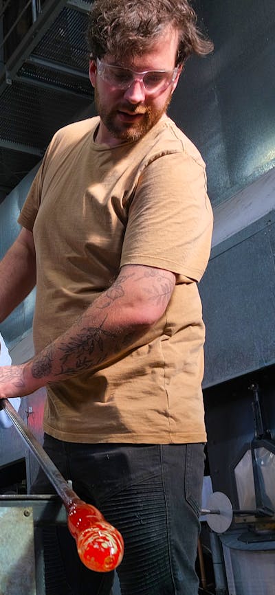 Participant and artist blowing glass