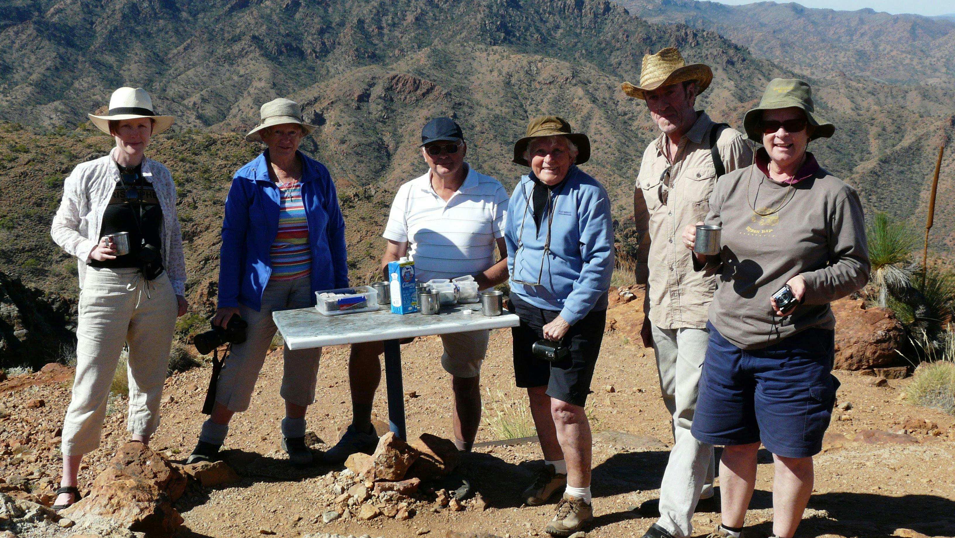 Group having morning tea with mountain ranges behind them