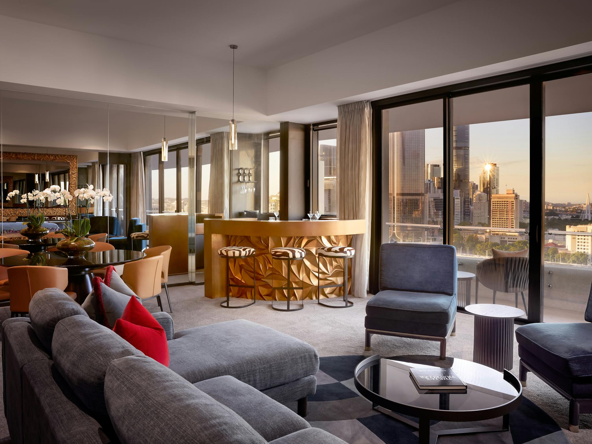 Spacious suite with sculpted gold bar, zebra stools, dining table and lounge seating at sunset Spacious suite with sculpted gold bar, zebra stools, dining table and lounge seating at sunset