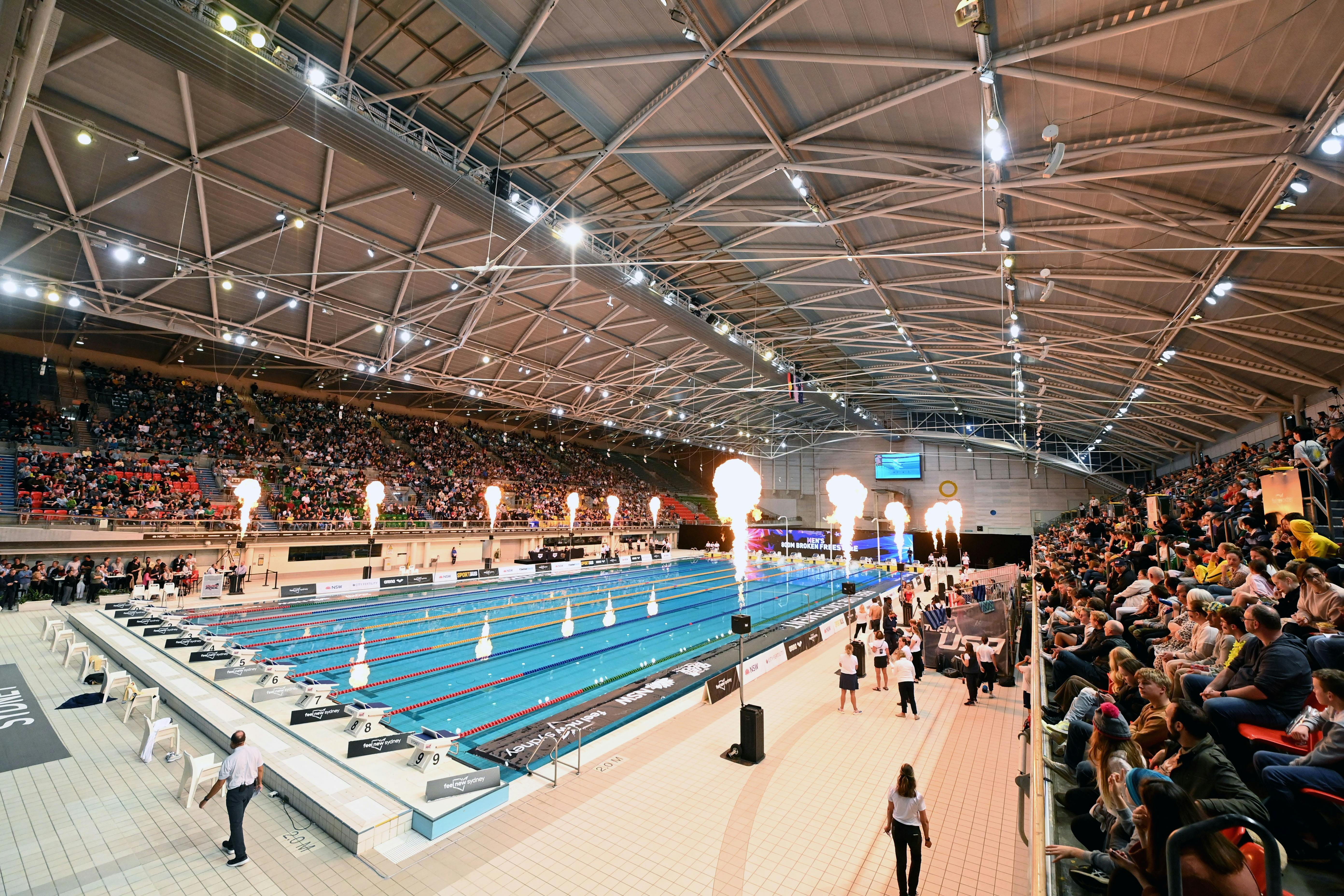 Phot depicts a wide angle shot of the Sydney Olympic Park pool with fans and pyrotechnics on display