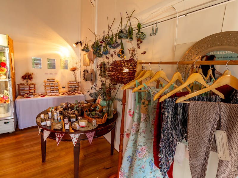 Handknitted shawls scarves hats , dried flowers adorn the walls, and soaps are on display.