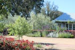 Picture of front driveway entrance with a house and garden in the background and gardens.