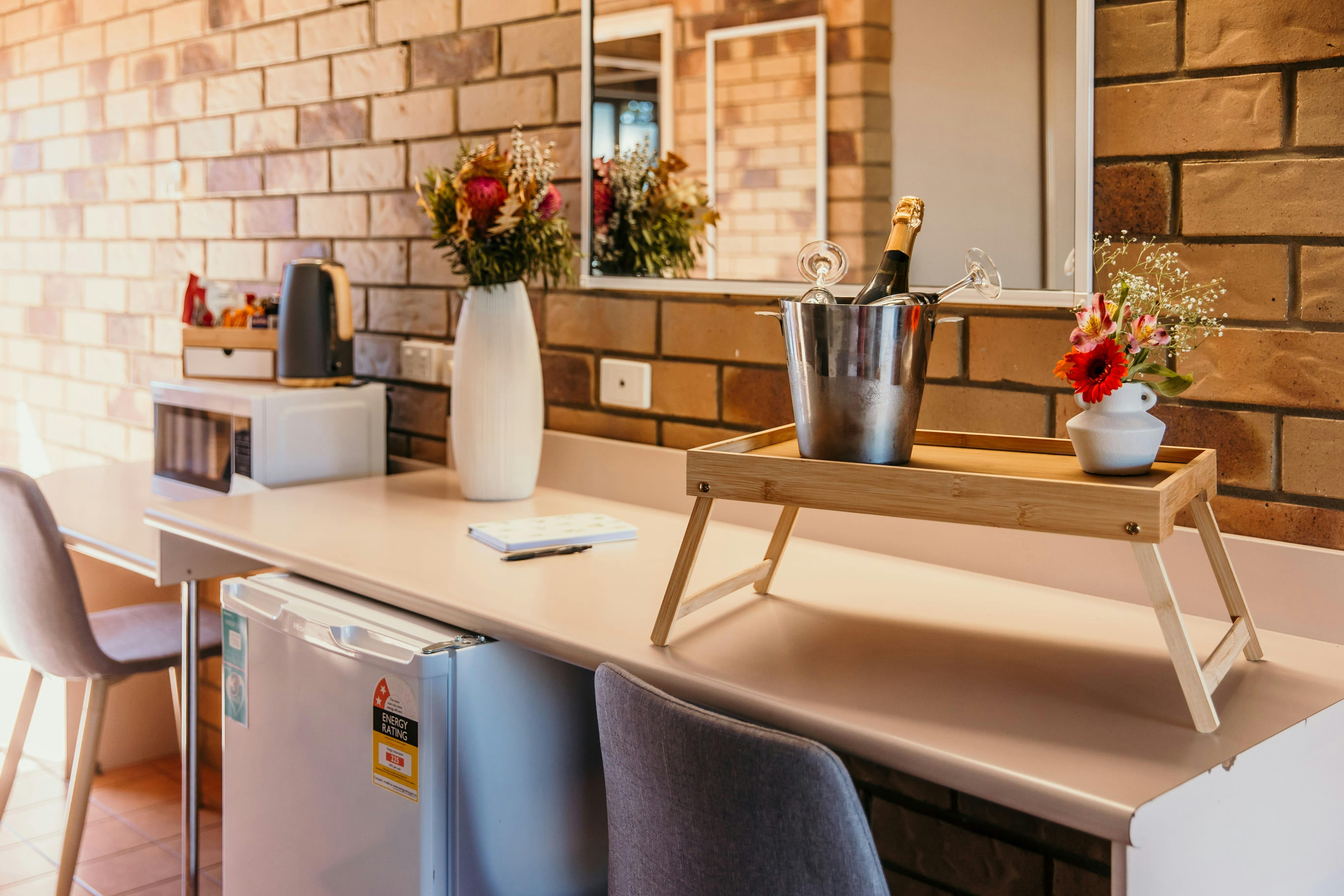 Desk, refrigerator, microwave and a tray with a champagne ice bucket.