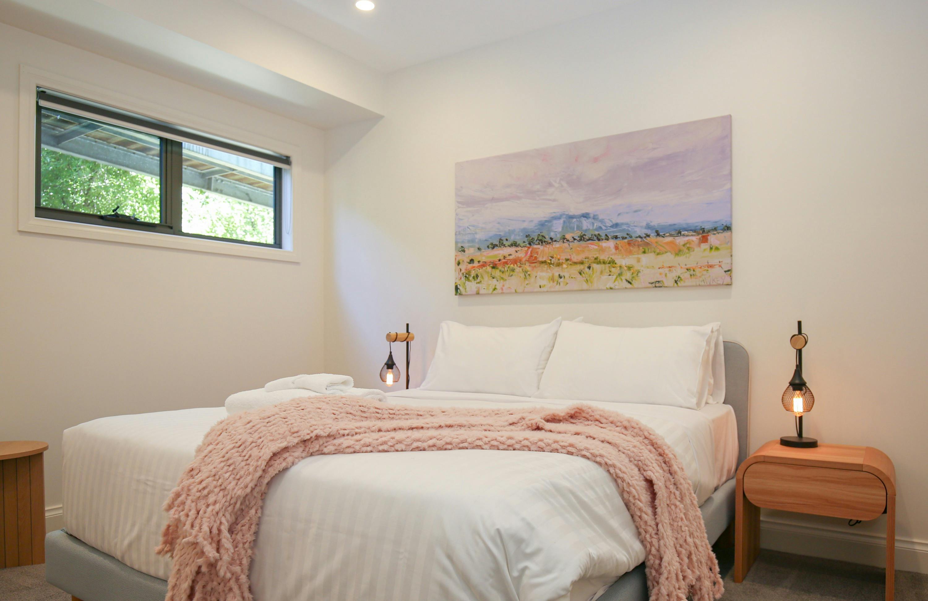 Northern Exposure Bright bedroom featuring bed, table side lamps and decorative painting