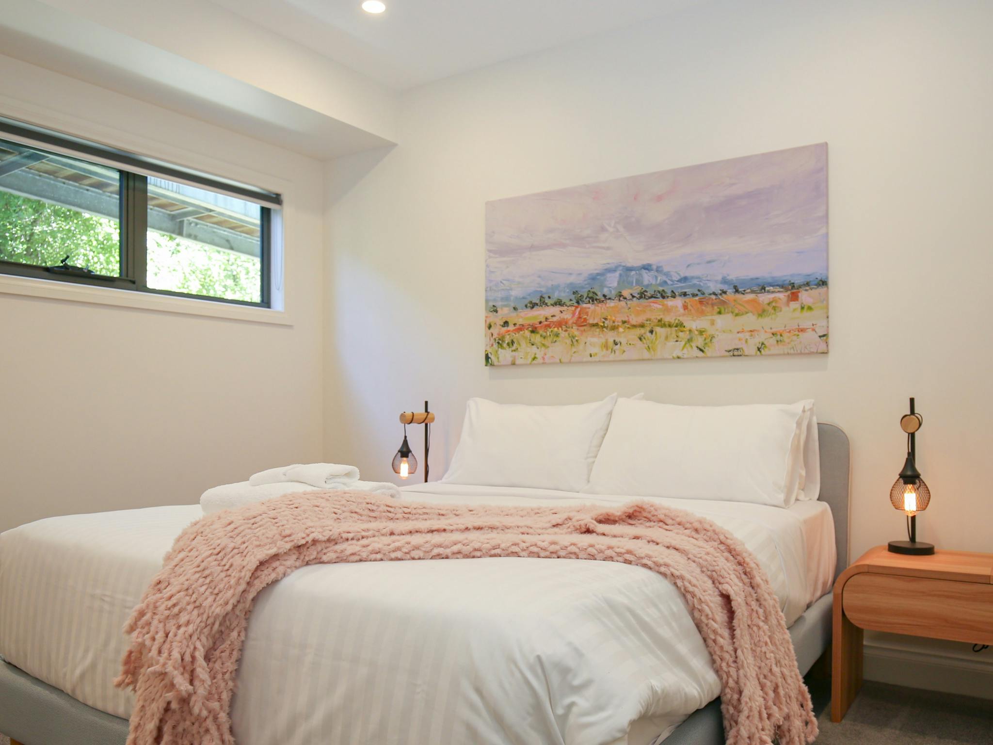 Northern Exposure Bright bedroom featuring bed, table side lamps and decorative painting