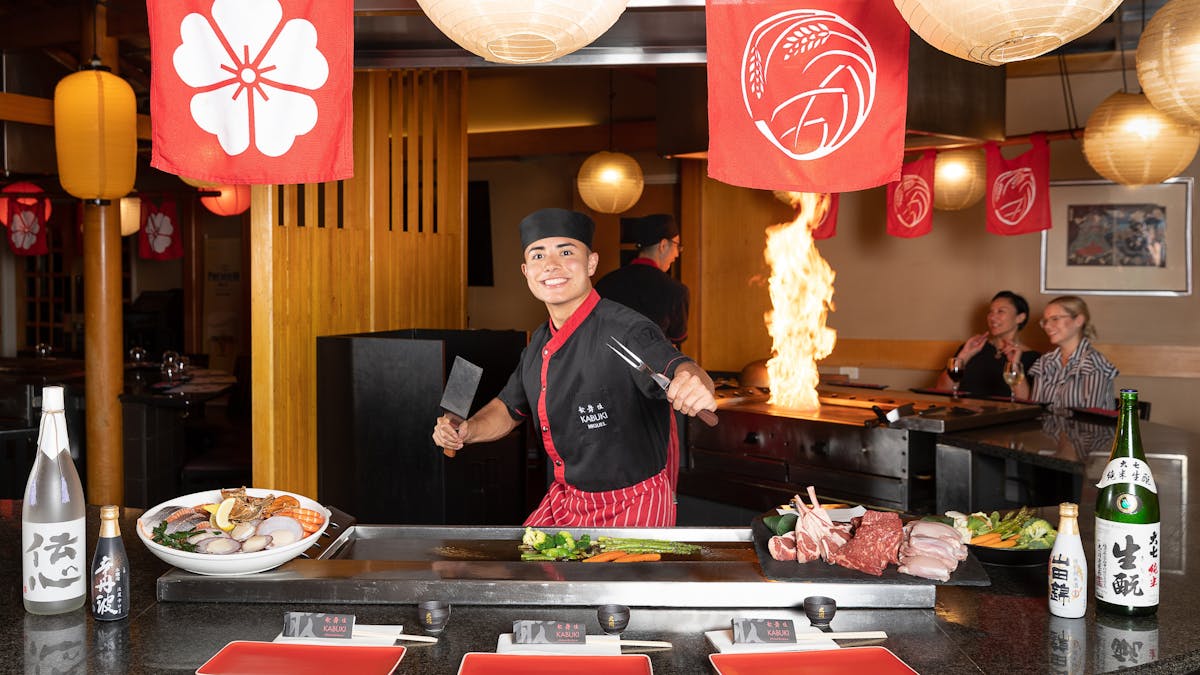 Chef behind a teppanyaki smiling at the camera