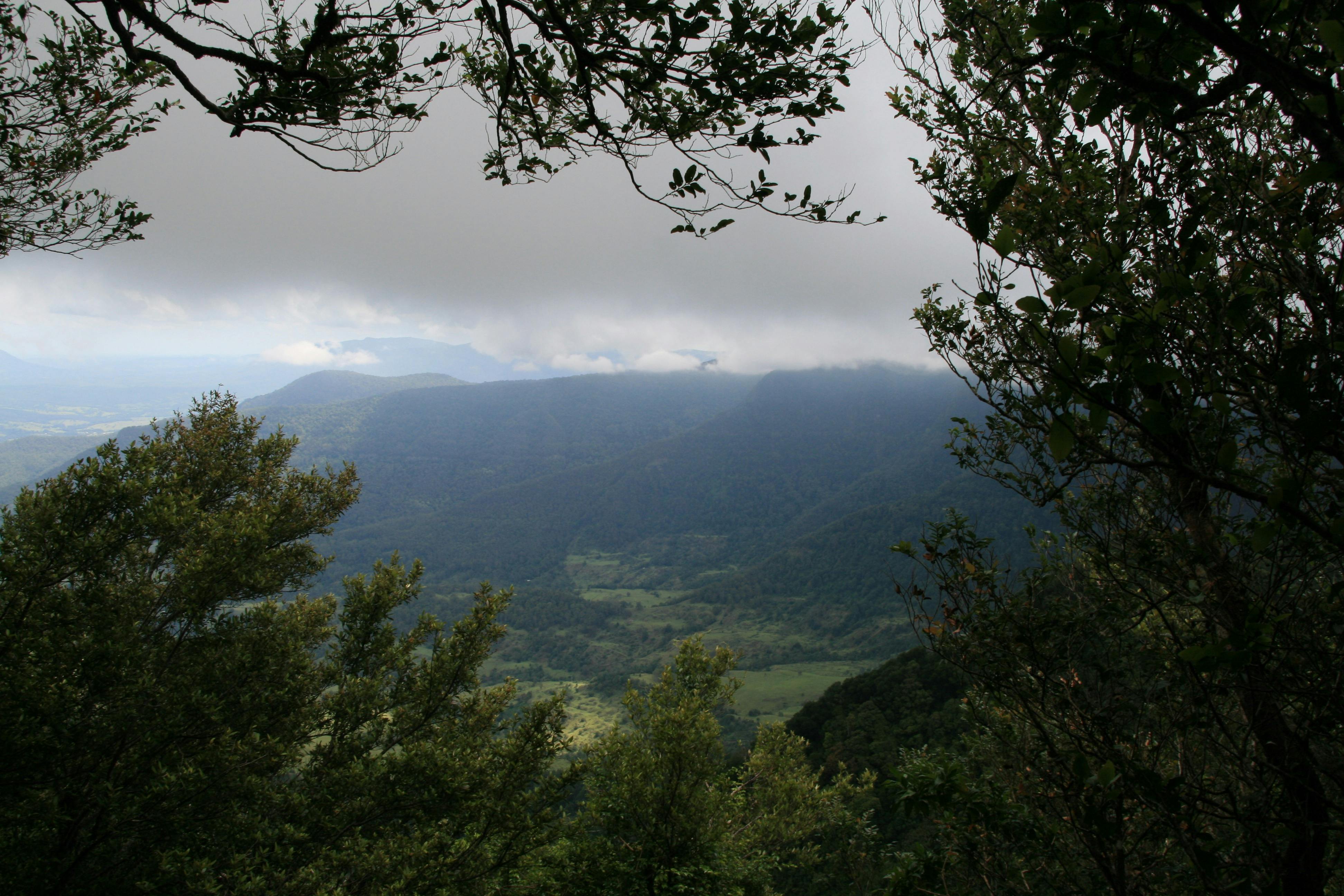 View over valley toward distant mountain shrouded in fog.