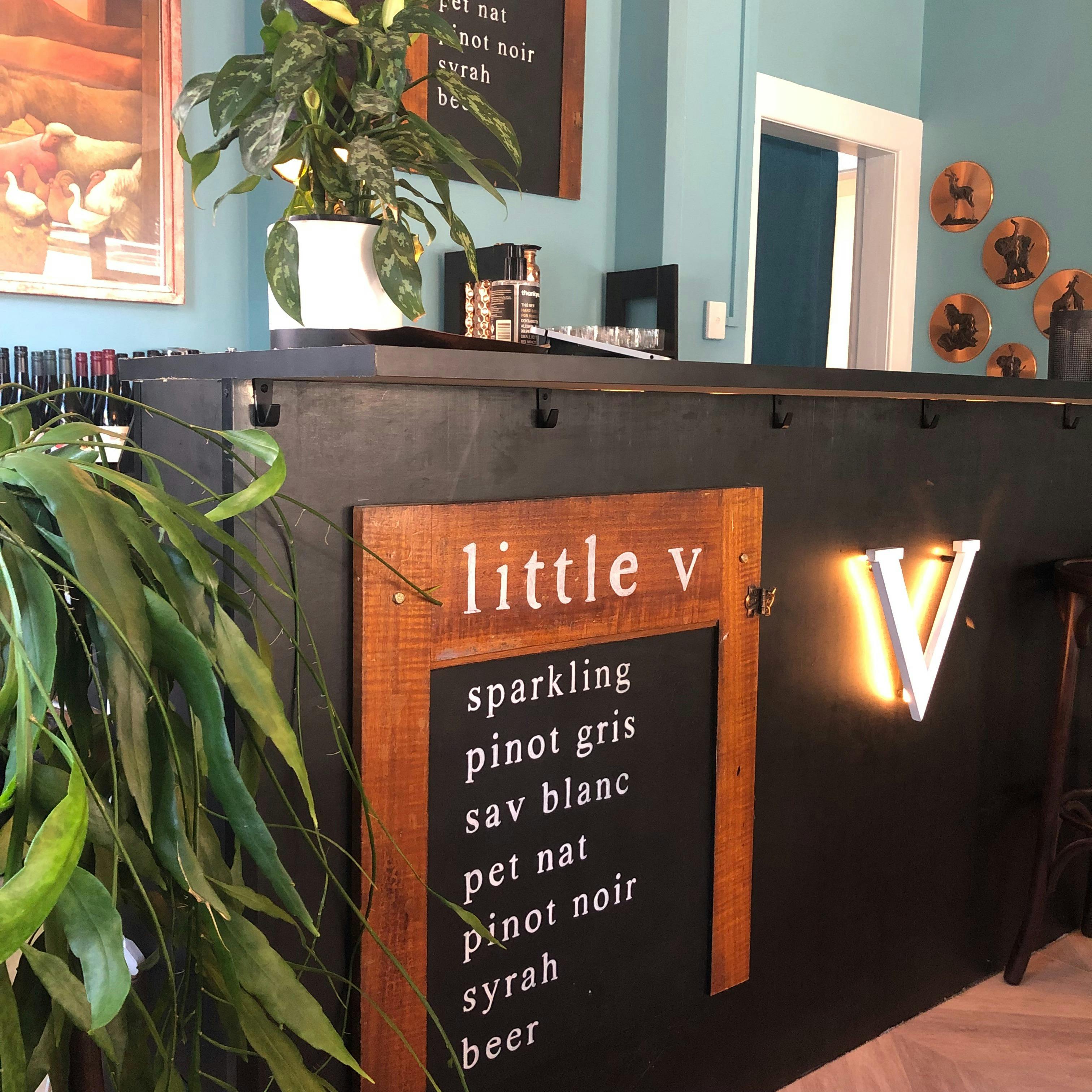 This is a photo of the long black bar at the back of the restaurant with a wooden sign listing wine