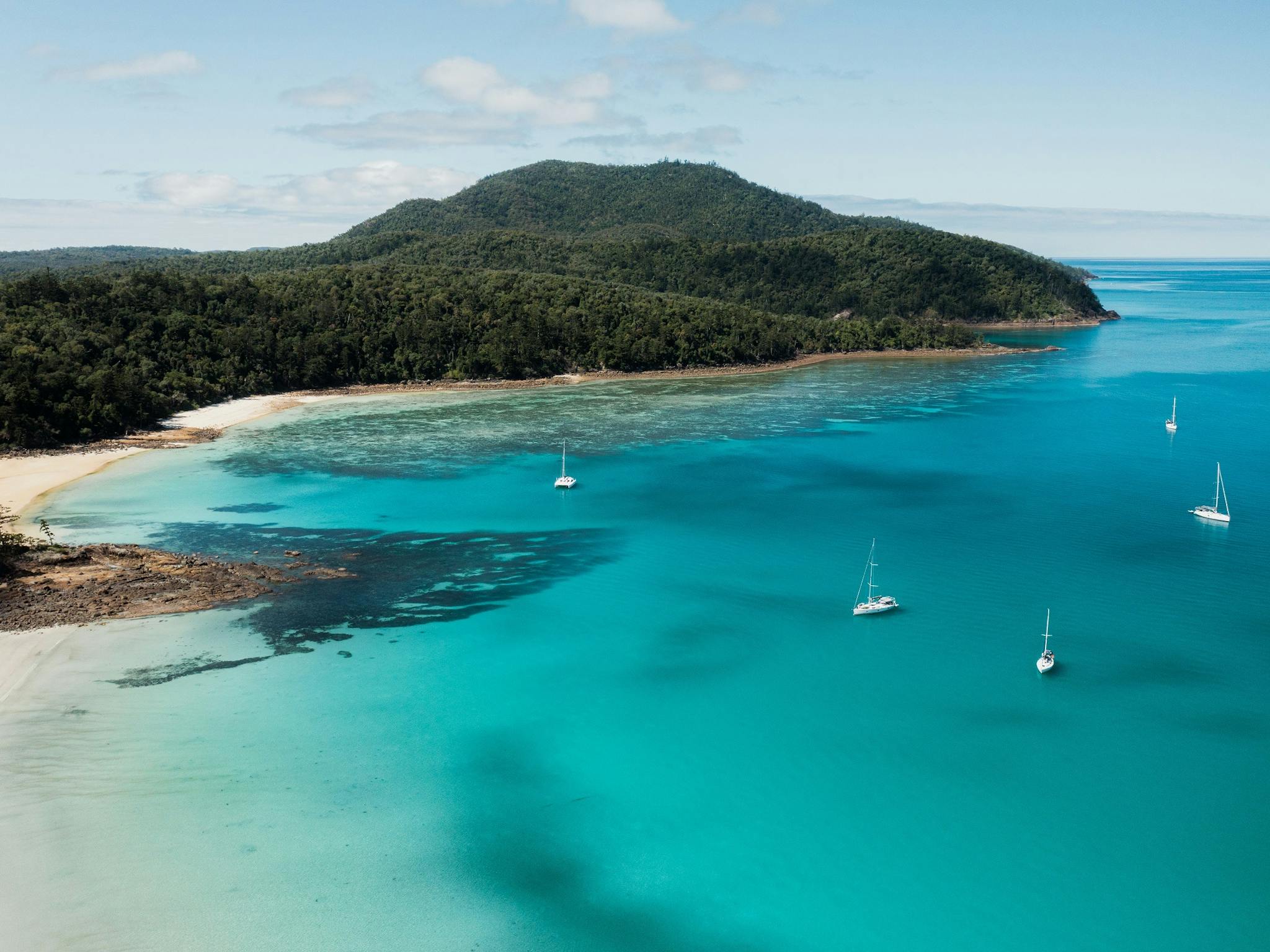 Aerial view of chance bay with sailing boats close to the beach and island hill covered in trees. Aerial view of chance bay with sailing boats close to the beach and island hill covered in trees.