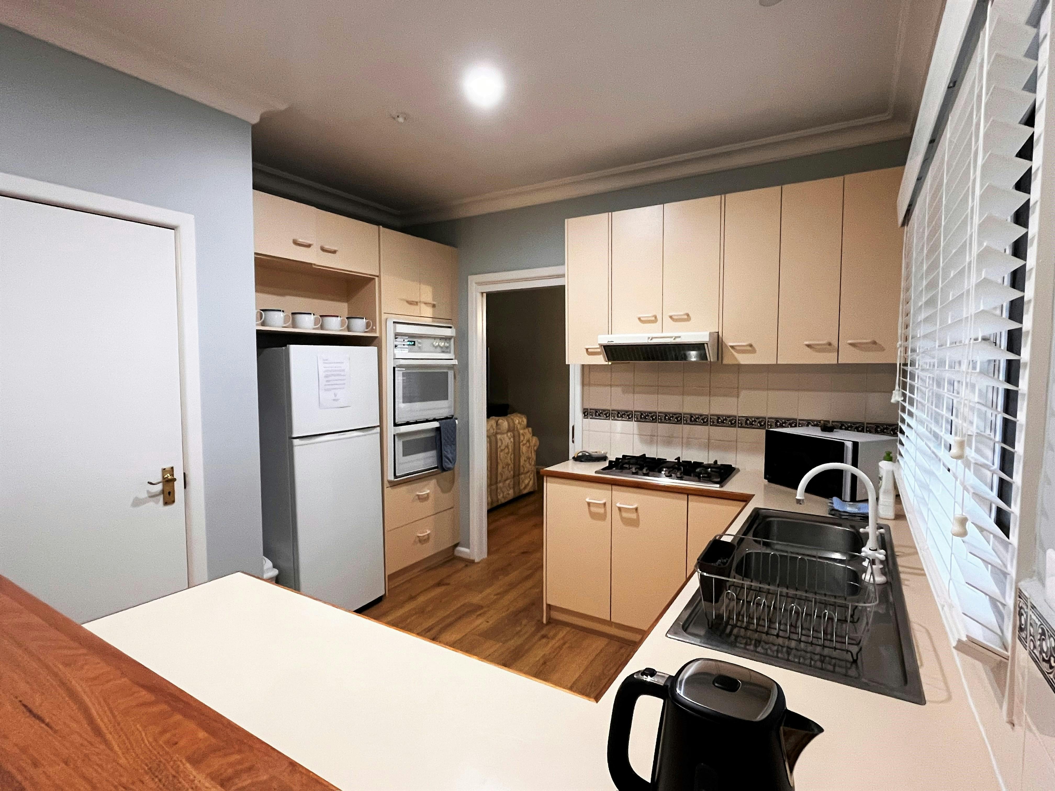 A cozy kitchen with beige cabinetry, modern appliances, and a spacious counter, perfect for cooking.