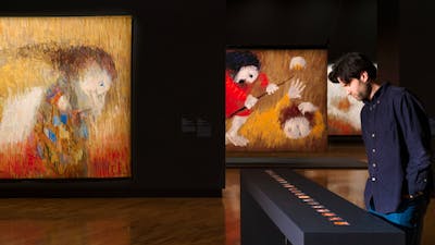 View of inside art exhibition with large tapestry and a visitor