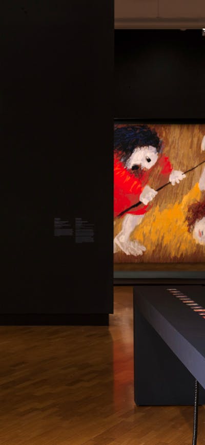 View of inside art exhibition with large tapestry and a visitor
