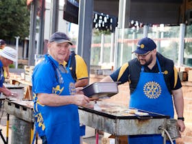 Two men from the Mount Gambier Lakes Rotary Club cook a BBQ