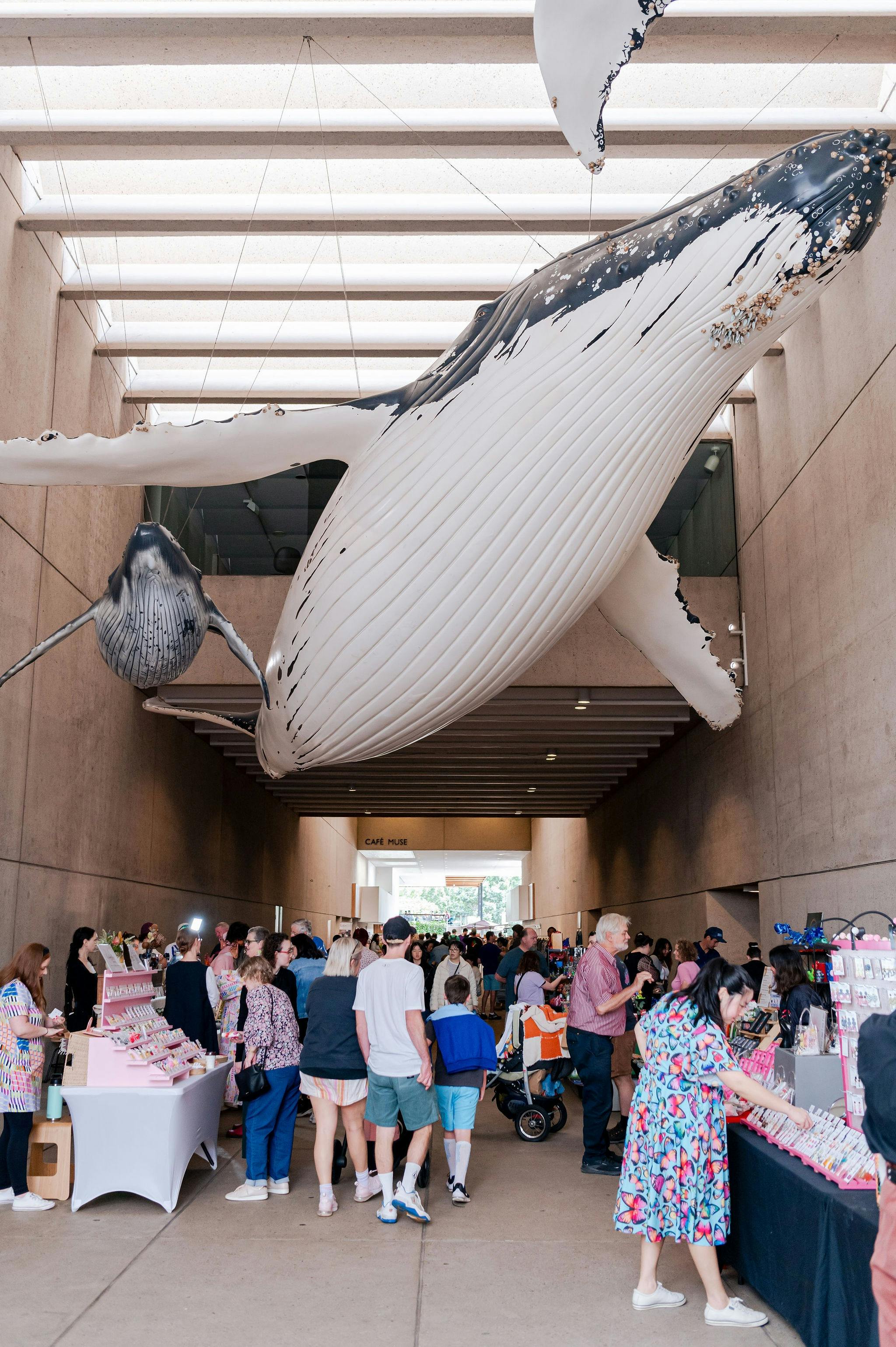 The market bustling with shoppers under the flying whale installation