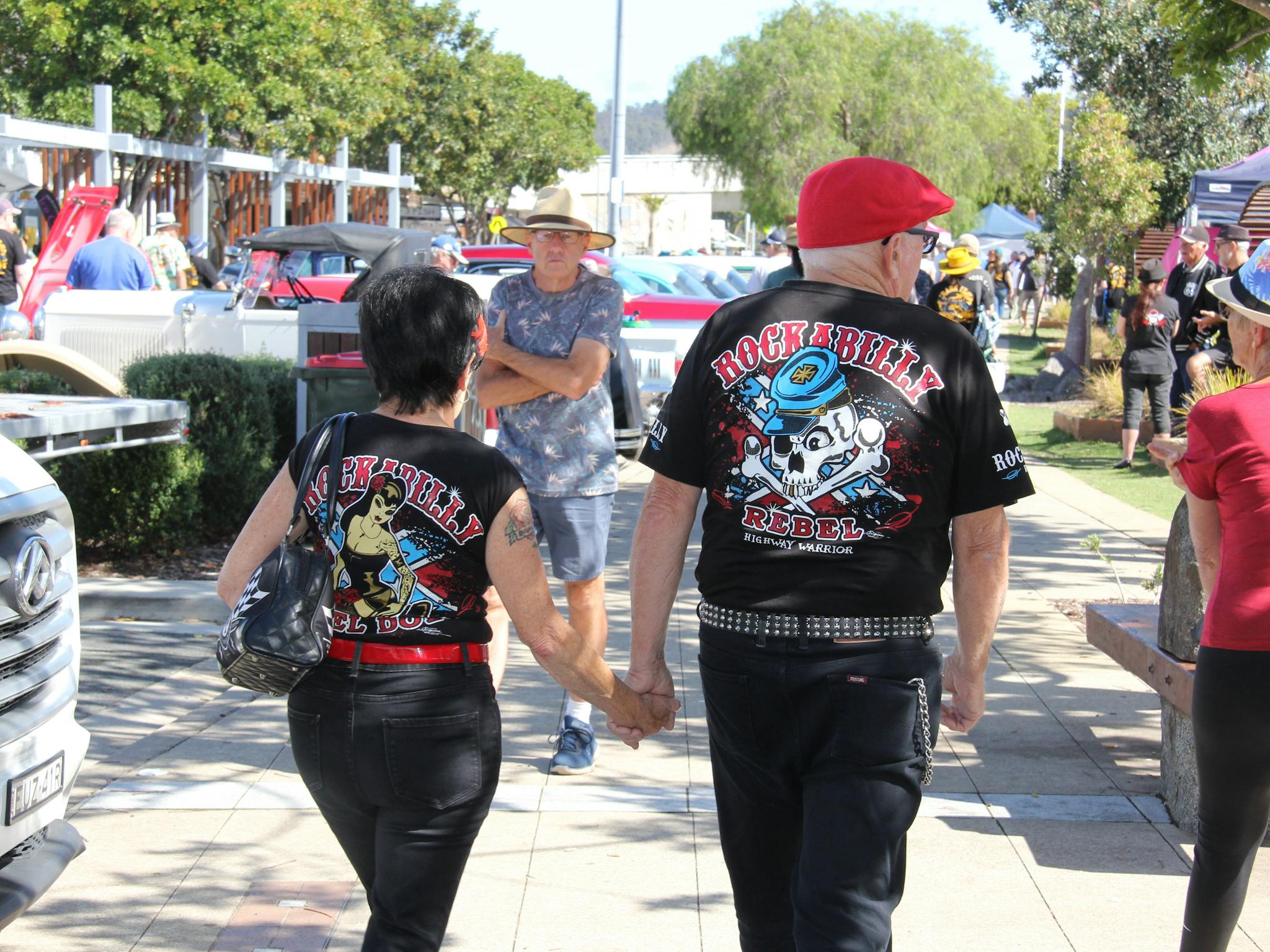 A couple dressed in Rockabilly style clothing walk down the street