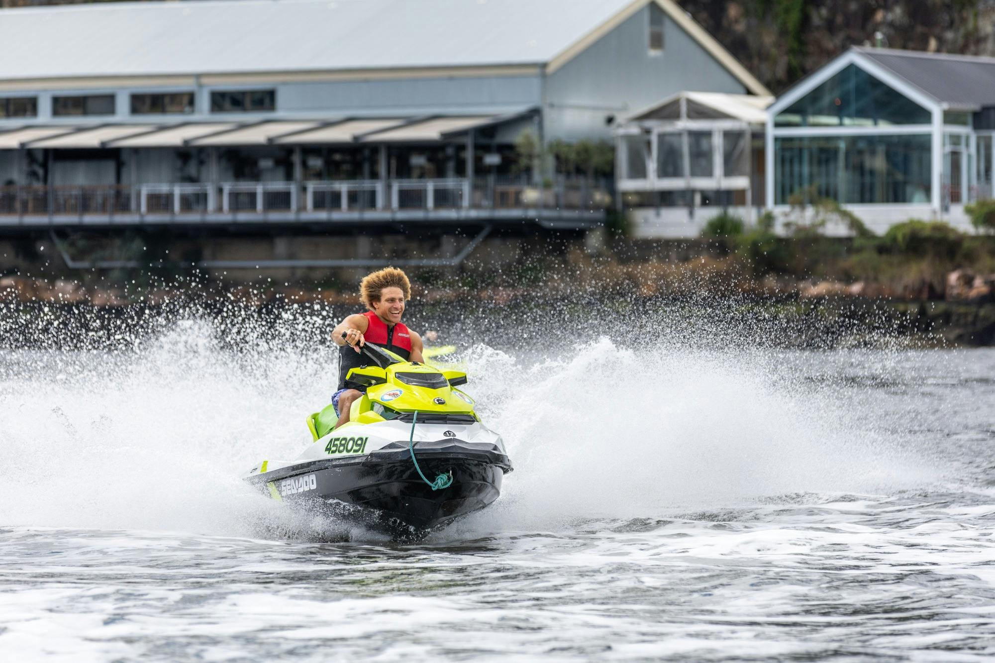 Male riding a jetski near Howard Smith Wharves with water splashing.