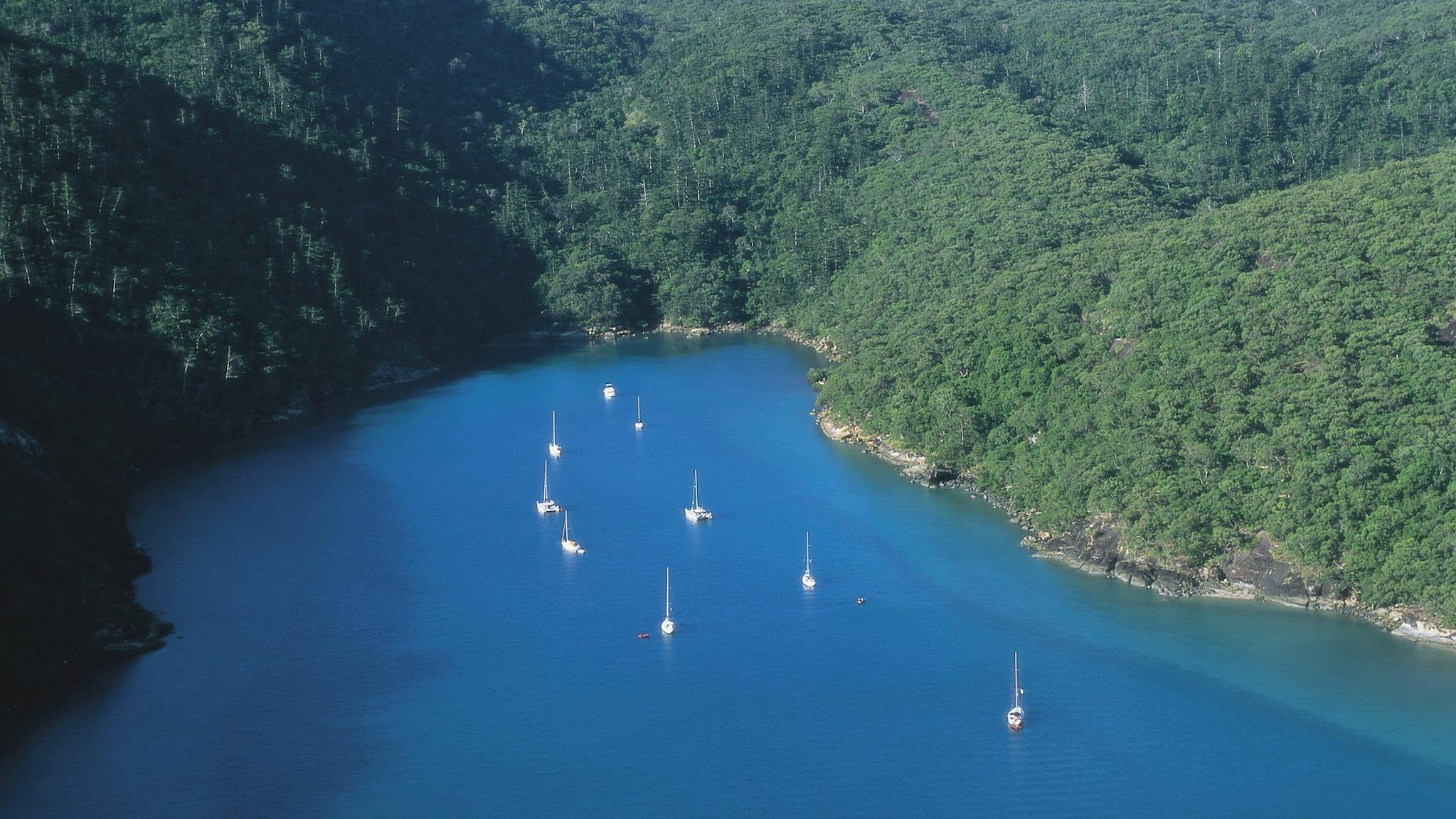 Sailing boats moored in Nara Inlet with tree covered hills of island in the distance Sailing boats moored in Nara Inlet with tree covered hills of island in the distance