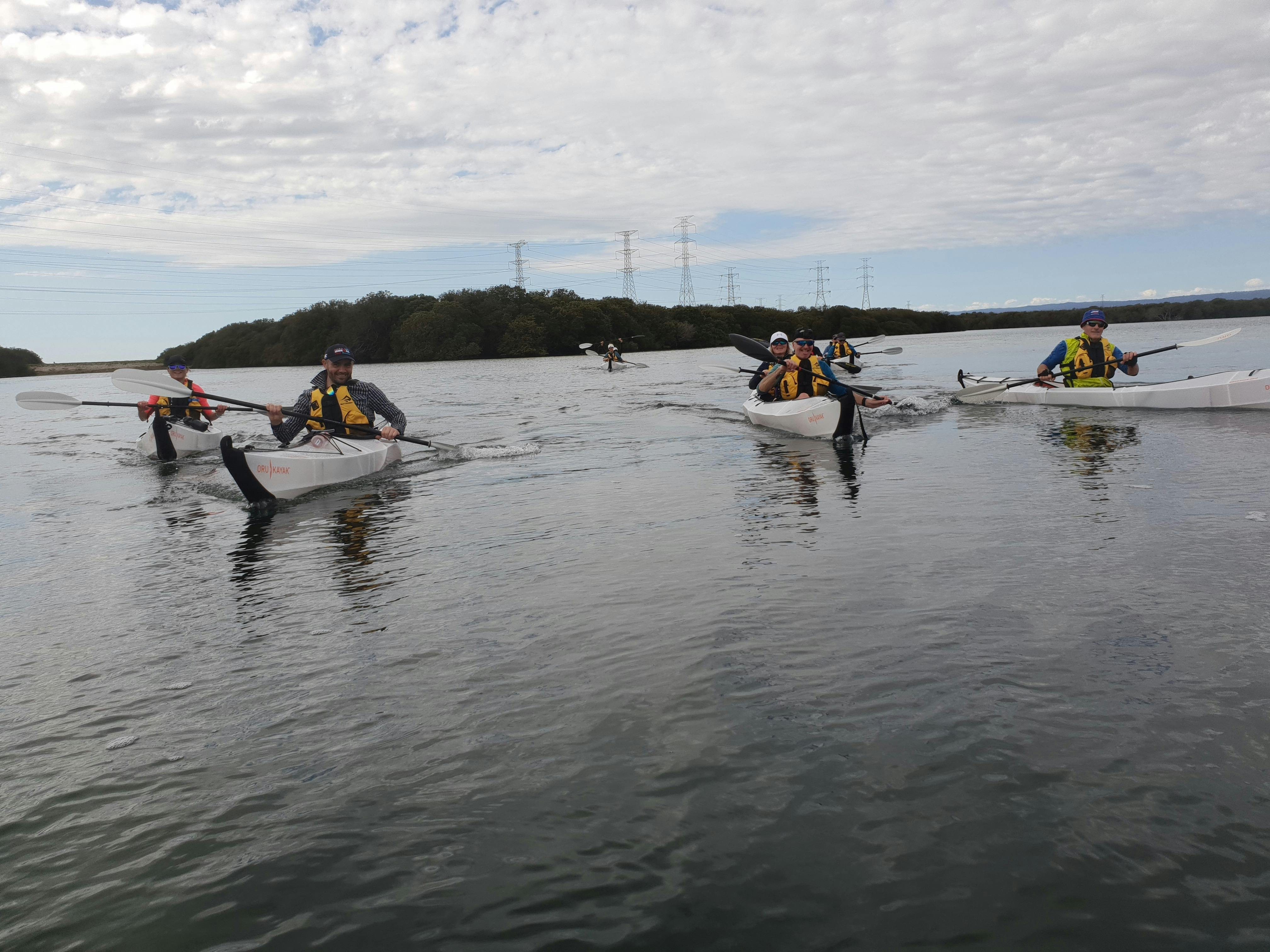 Group of 8 kayakers paddling on calm waters close together