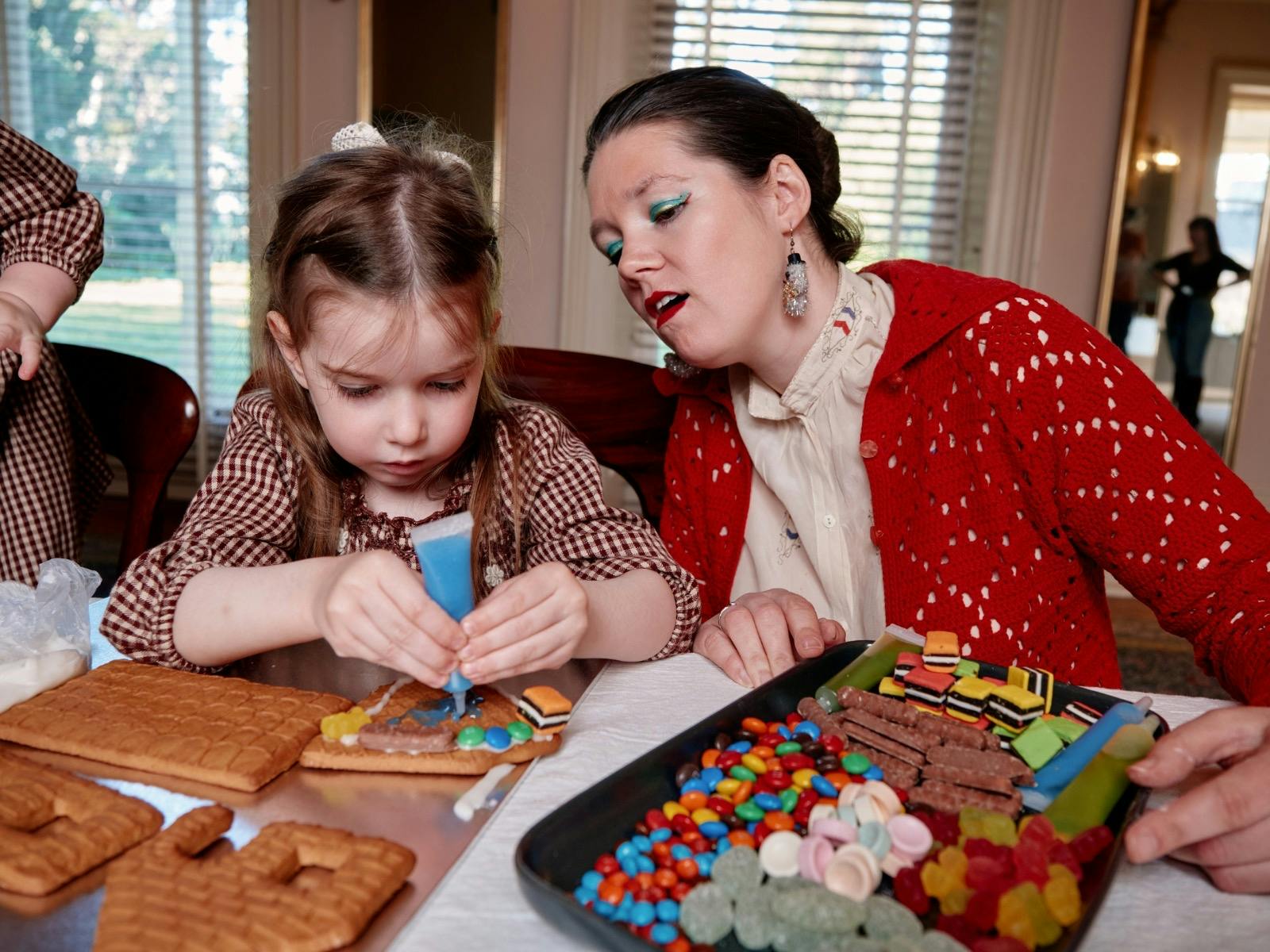 Gingerbread making class at Como House with girl piping icing on gingerbread house with woman
