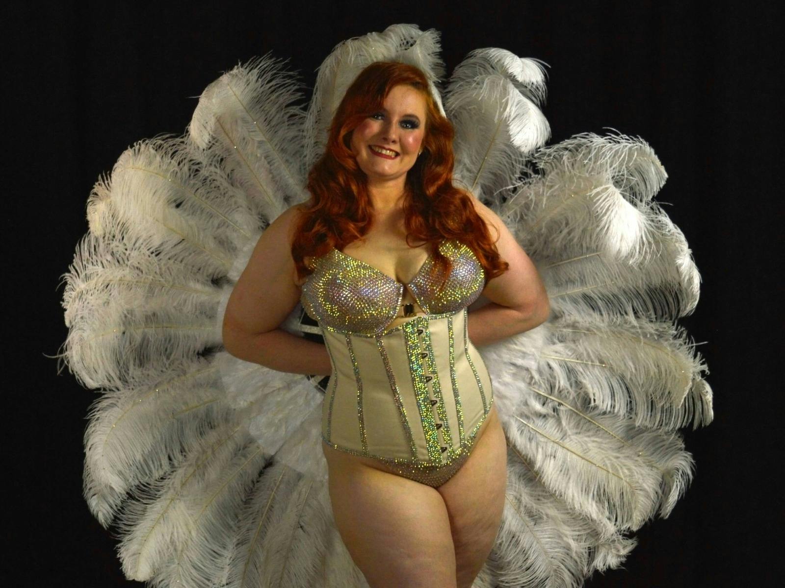 Selene Wilde is holding feather fans h=behind her back forming a circle