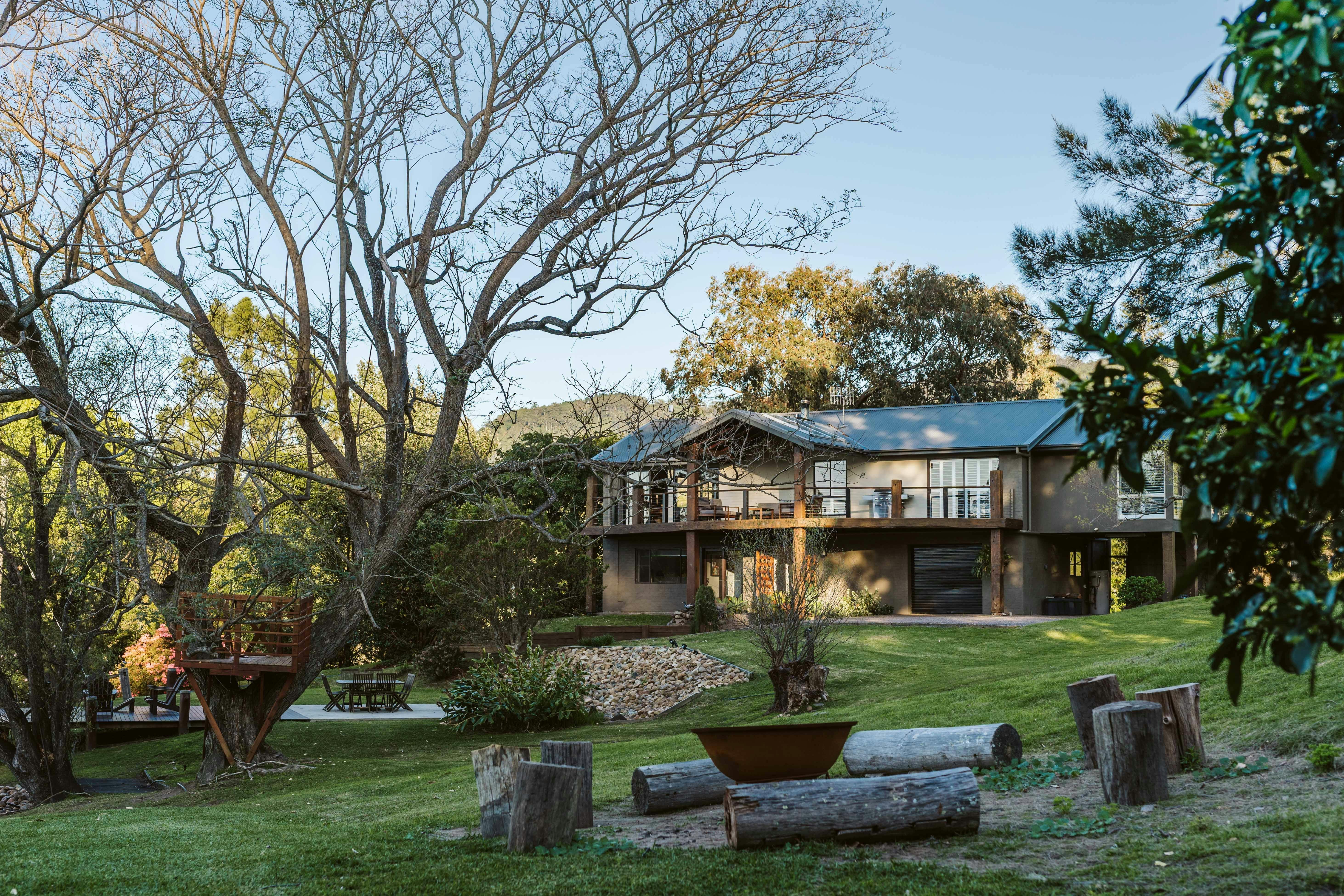 Image of property with firepit area in front view large tree sits to the left as the sun goes down