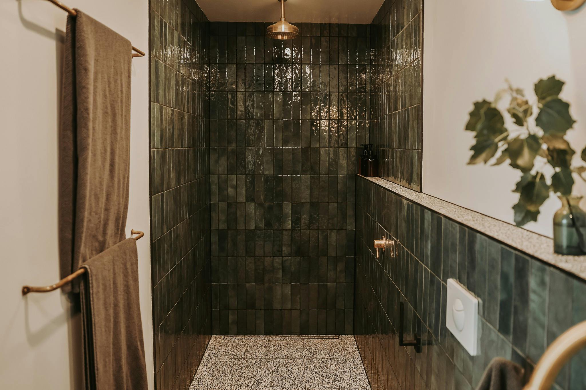 Bathroom with green tiles and brass rainfall shower