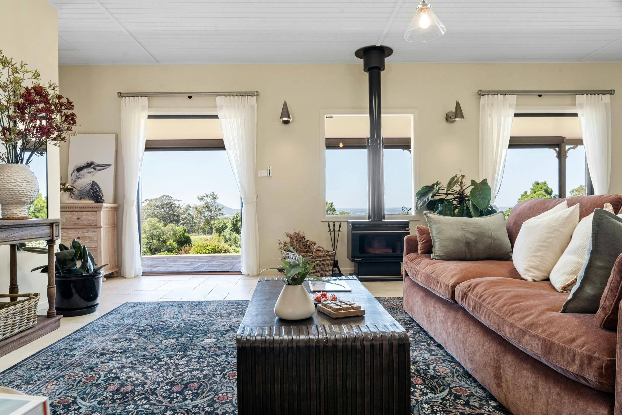 Plush rust coloured lounge and cushions, coffee table, rung and fire place, french doors