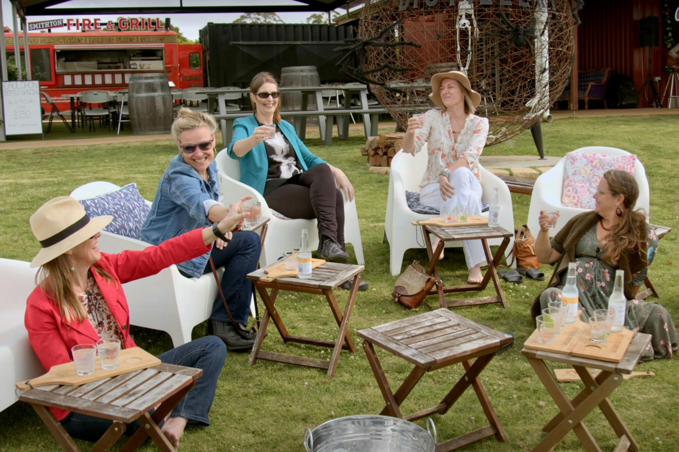 A group of women sitting on the lawn at Cauldron Distillery sipping gin