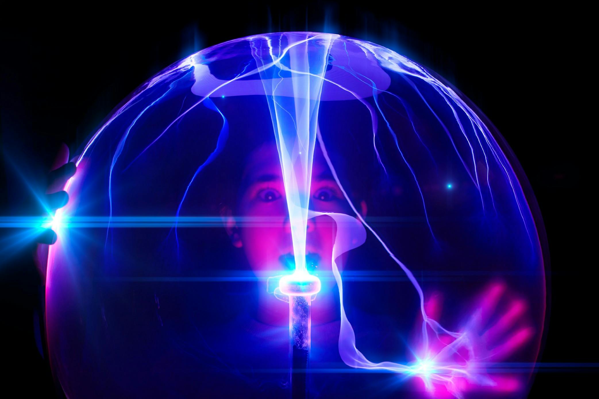 Child standing behind plasma ball exhibit