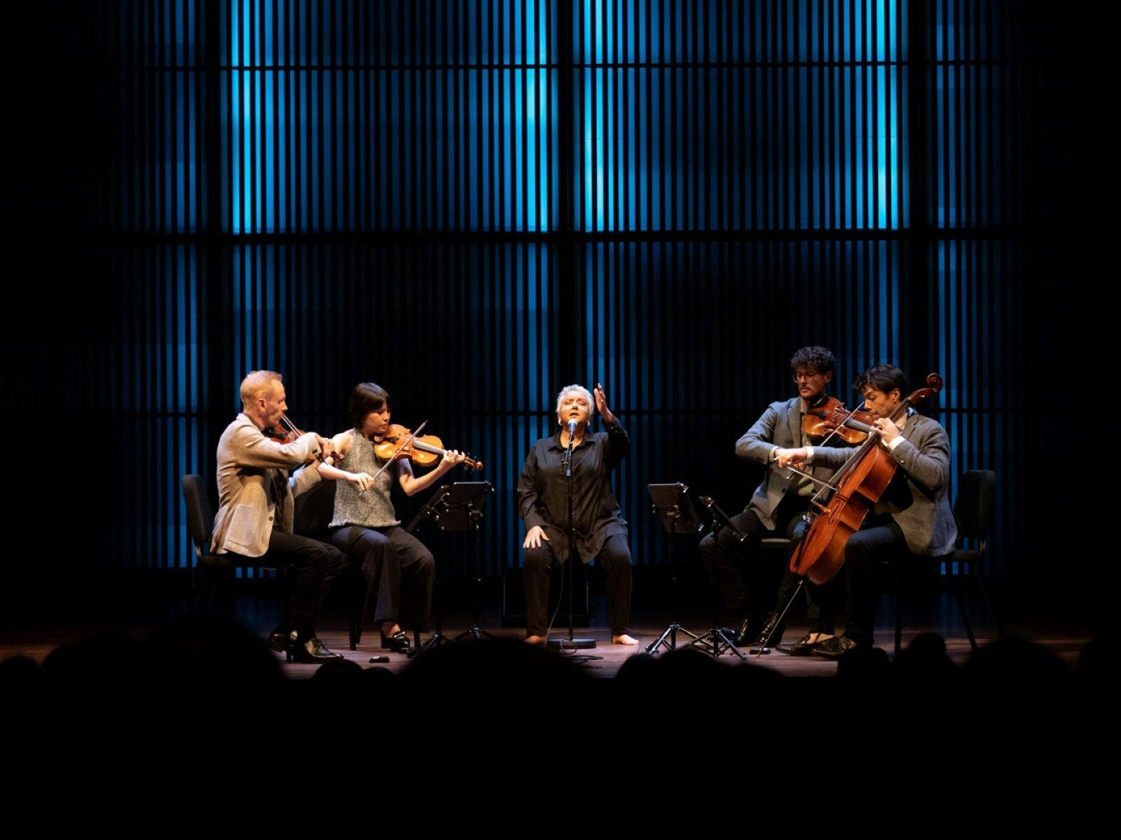 Dr. Lou Bennett AM performing with string quartet on stage