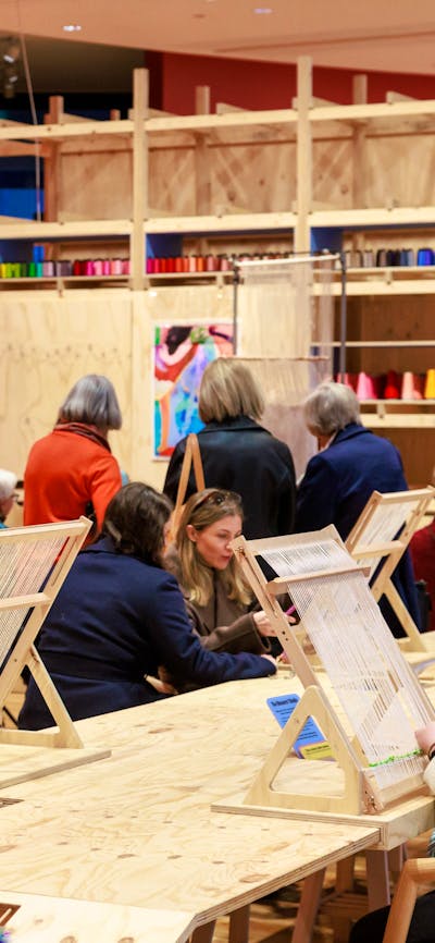 People sitting at a table weaving