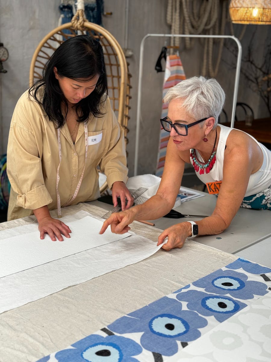 1 woman showing another how to make a lampshade