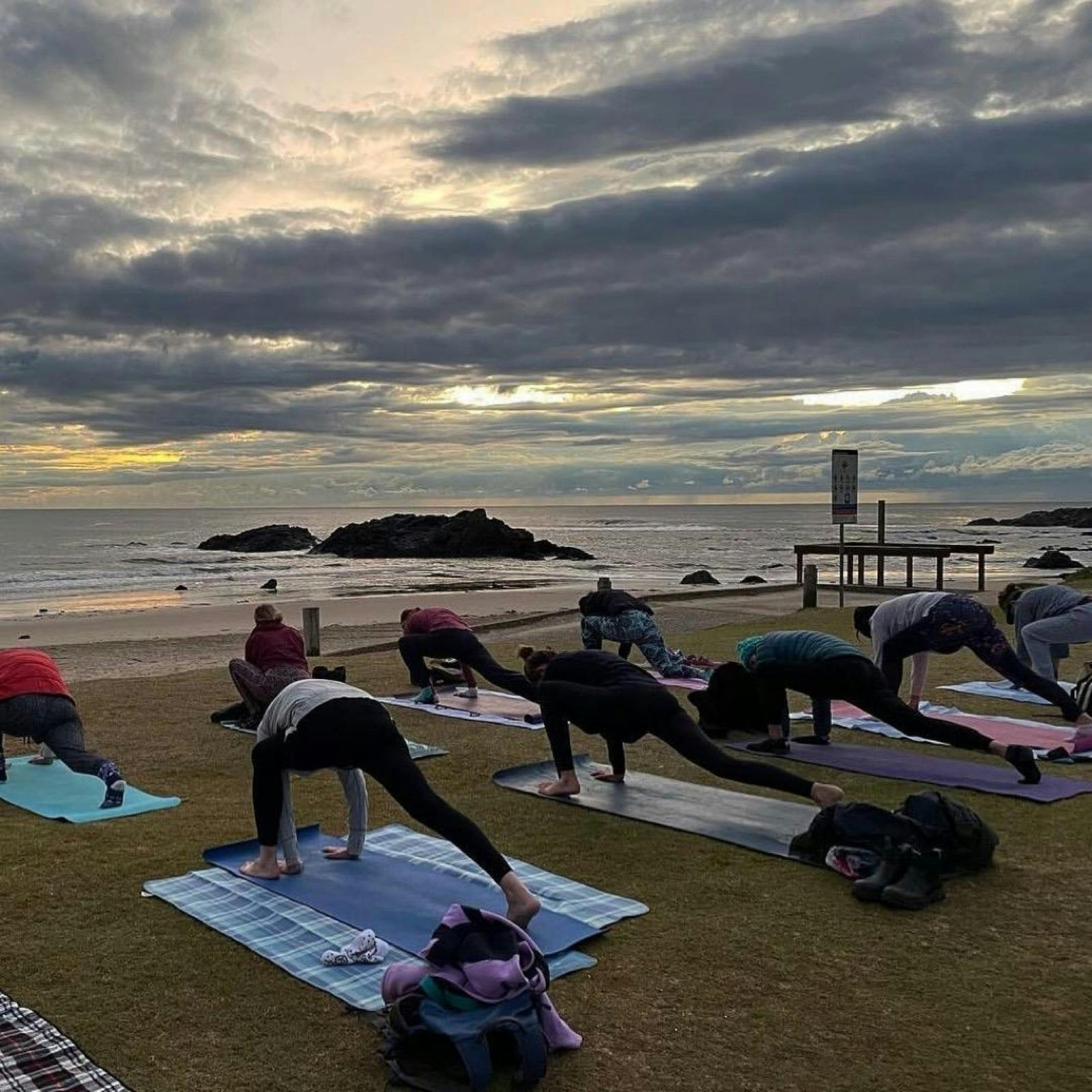 people doing yoga by the beach at sunrise