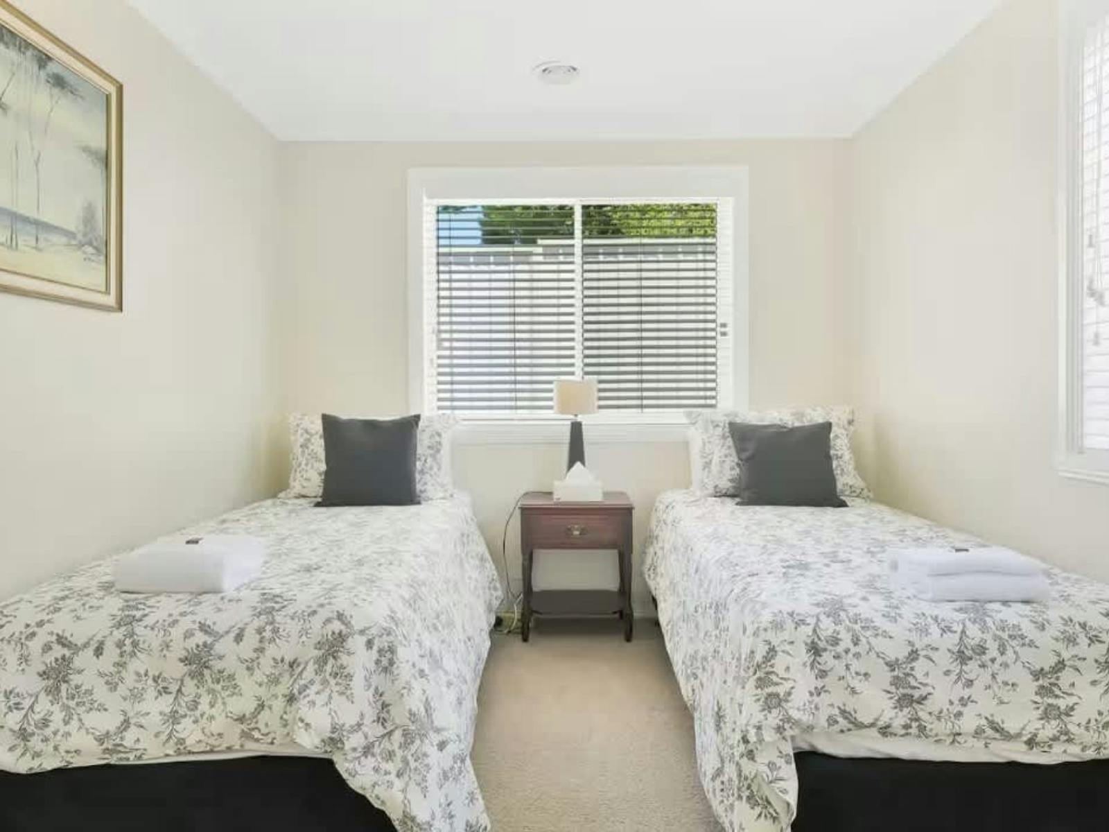 Bedroom with 2 singles, a side table, large window and an artwork