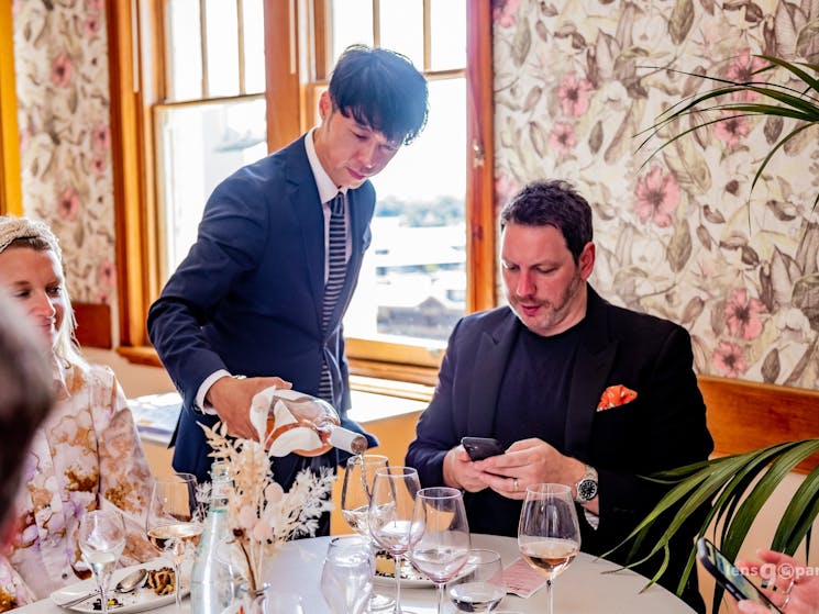 A waiter pours a patron a glass of red wine in the resturant