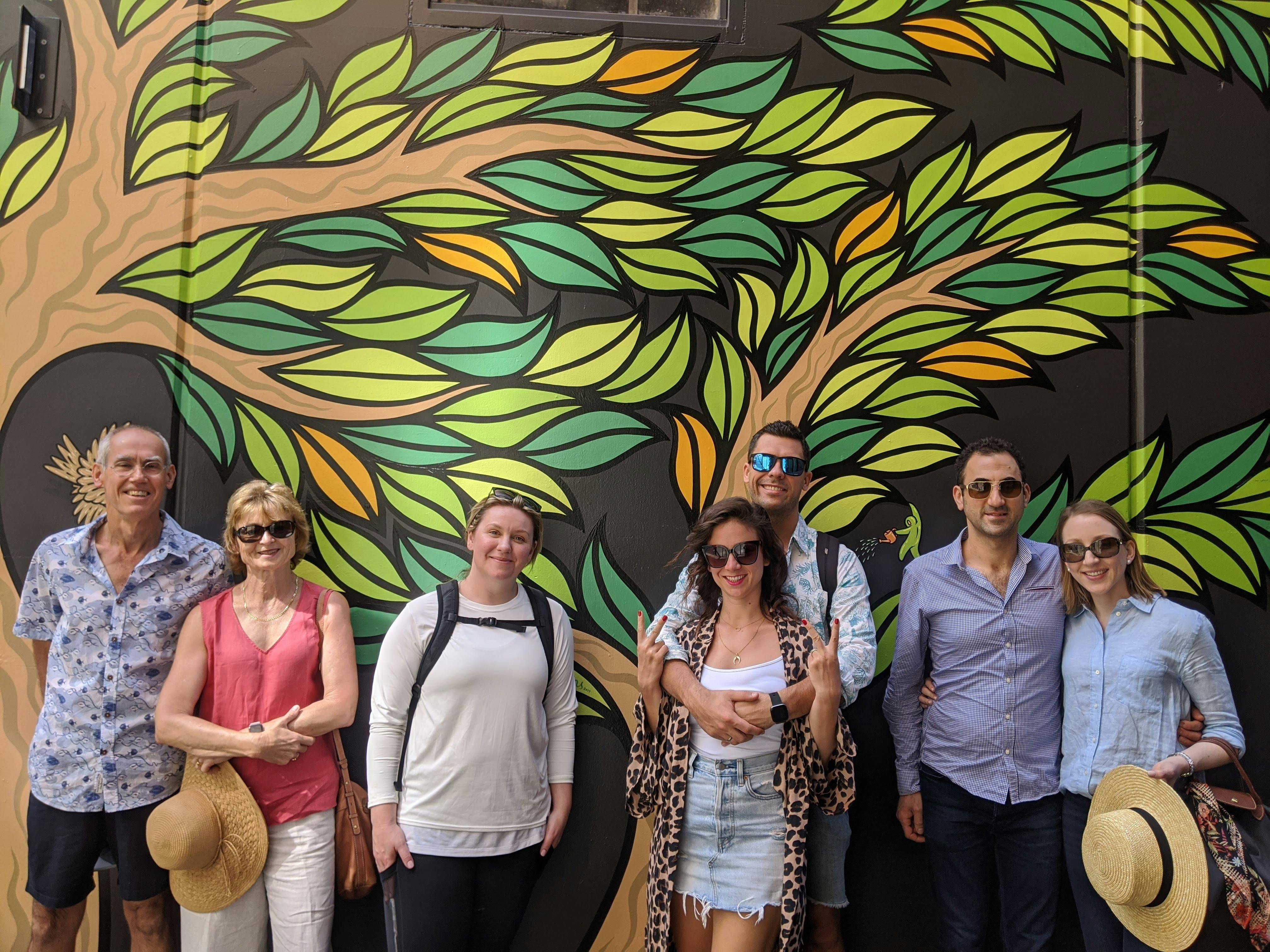 tour group smiling infront of vibrant green wall mural