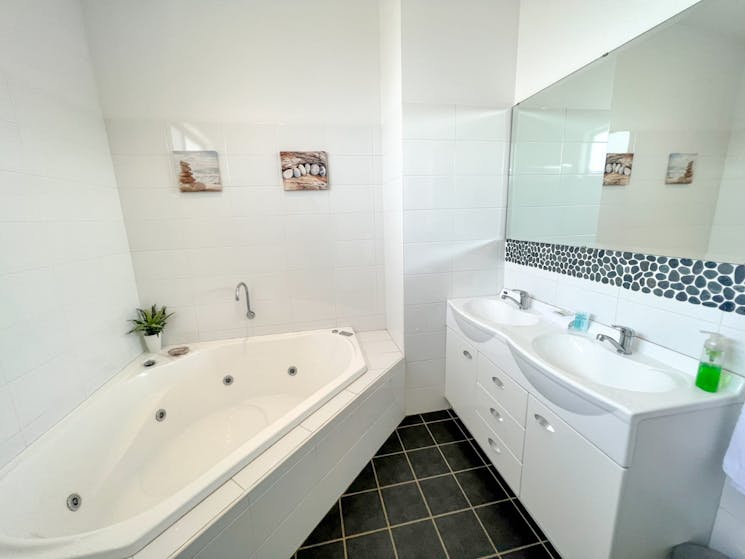 The bathroom features a corner spa bath, the perfect place to unwind at night