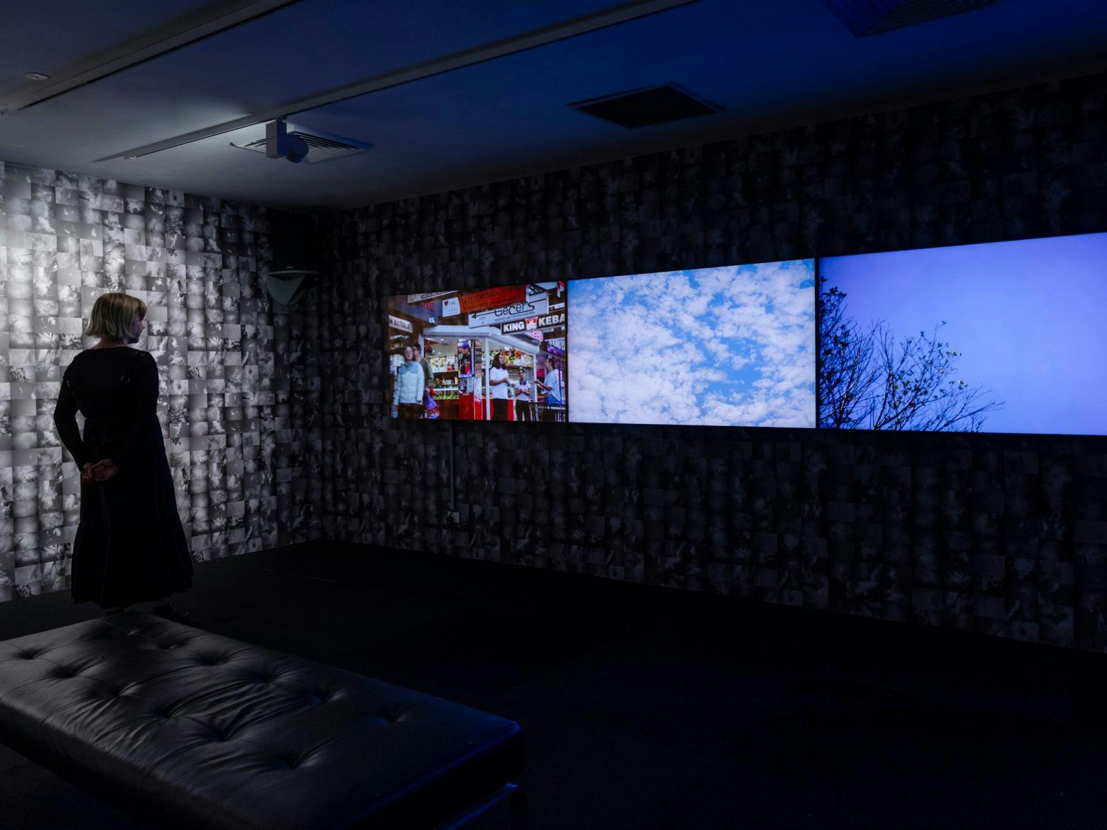 Video installation of ‘The Sky Between Us’. The walls have a photo collage of images of the sky