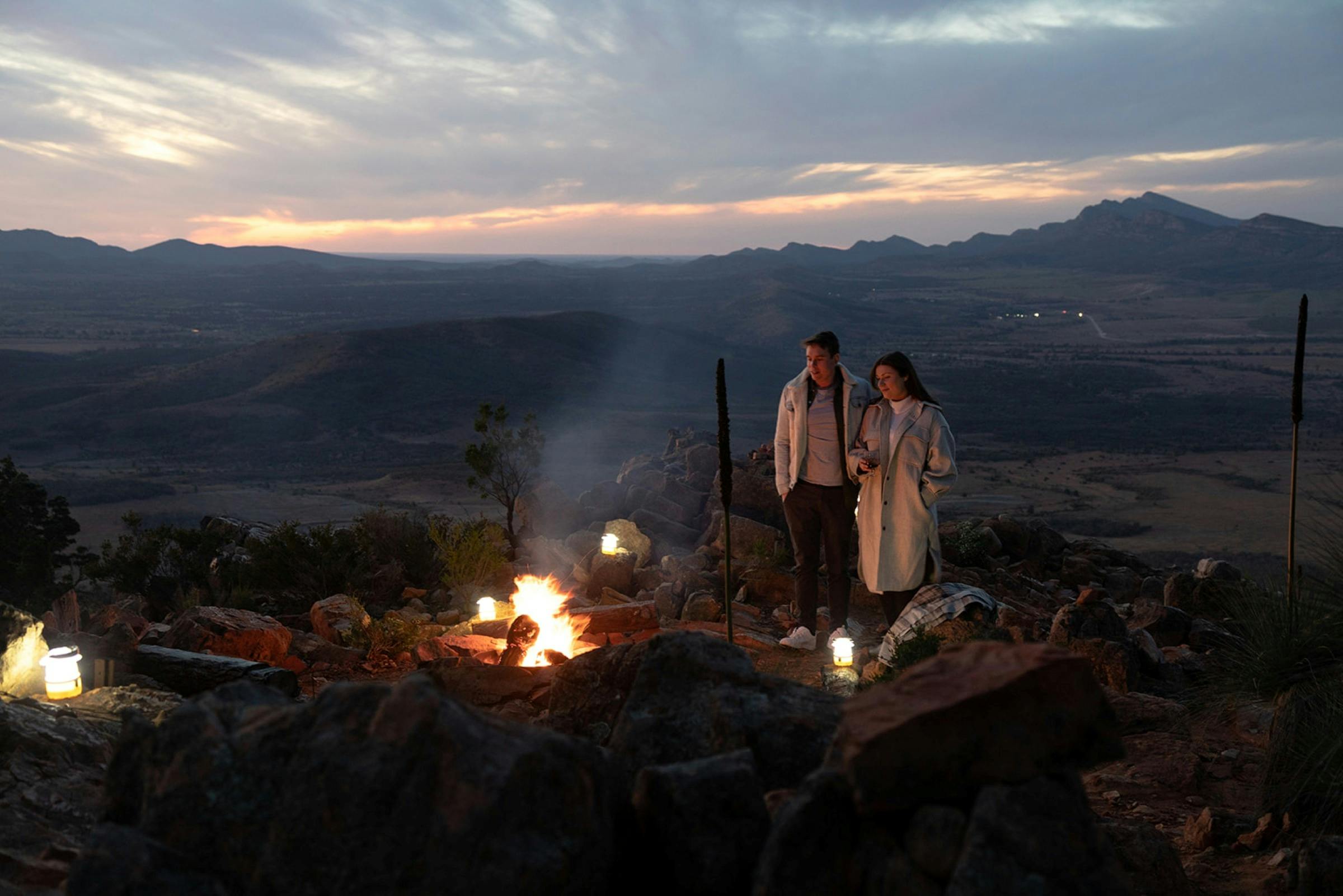 Couple on a heli-camping experience having dinner cooked over a firepit on Chace Range