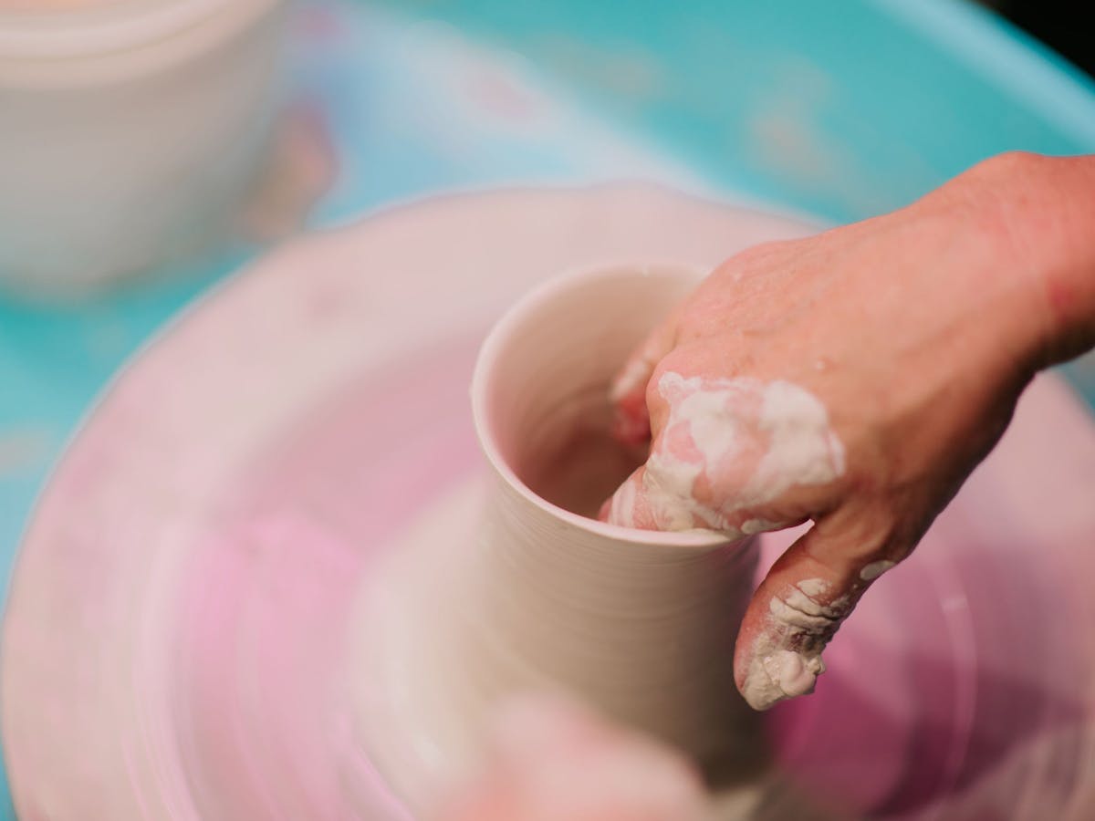 Hand in the centre of a clay cylinder wetting down the walls of the cylinder with water Hand in the centre of a clay cylinder wetting down the walls of the cylinder with water