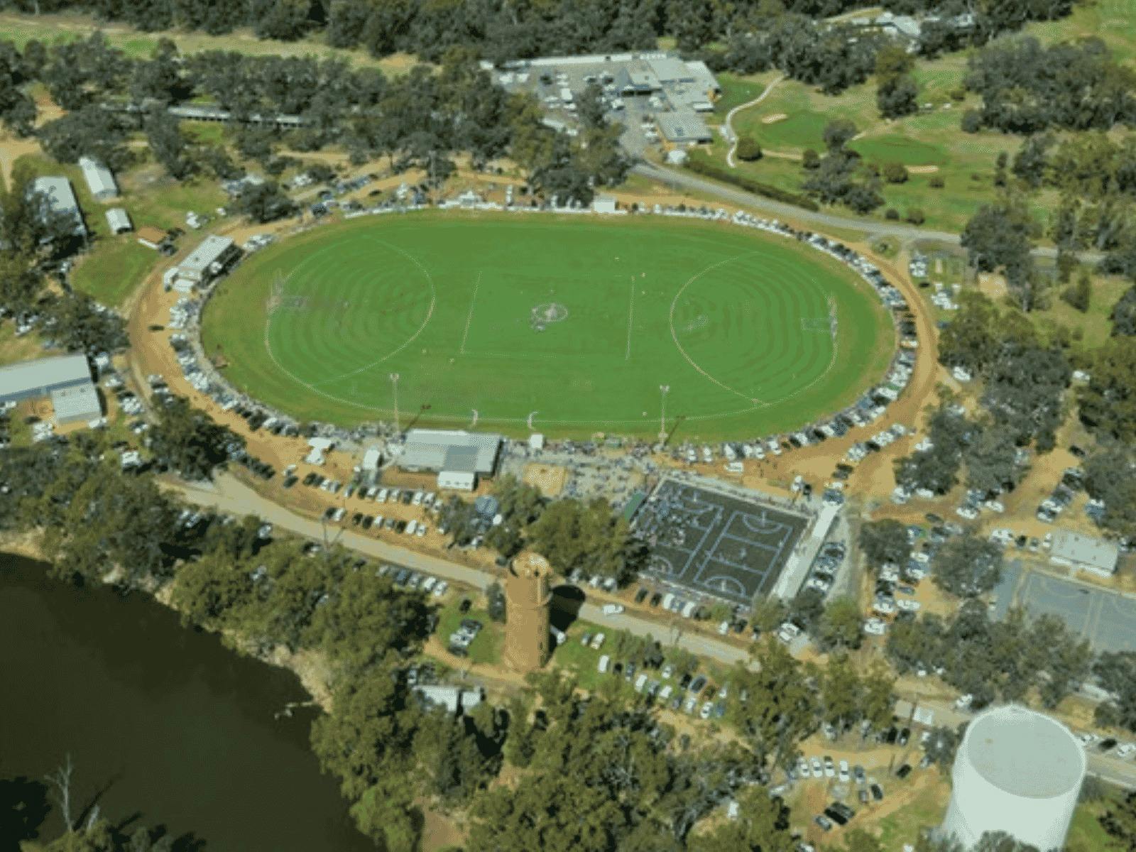 A large football oval is seen from the sky, alongside the river and some netball courts