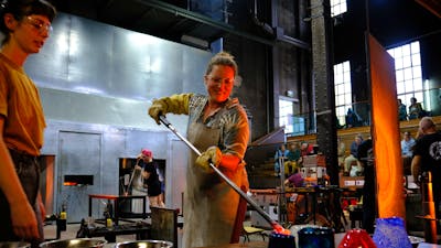 Participant in the Glassworks hotshop working with molten glass