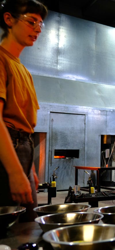 Participant in the Glassworks hotshop working with molten glass