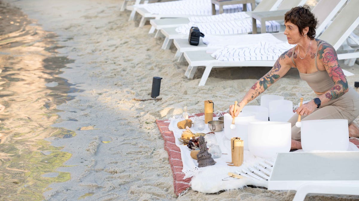 Aqua Sculpt sound bath practitioner playing sound bowls on the beach in the Gold Coast