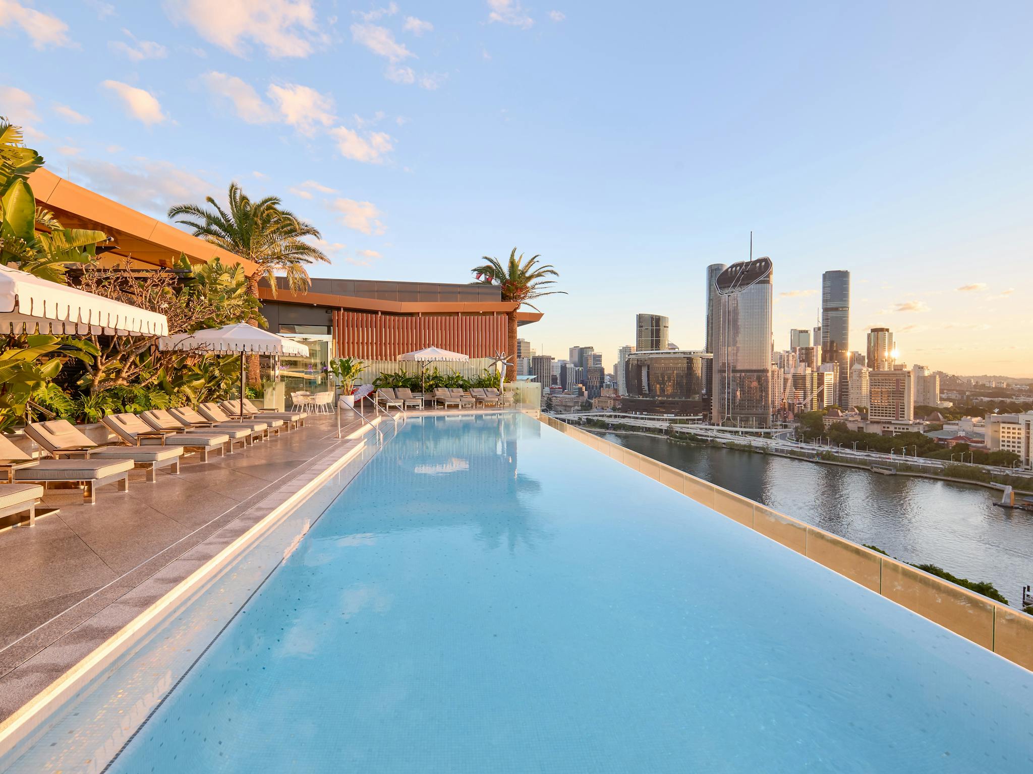 Rooftop infinity pool with sun loungers, umbrellas and panoramic views over Brisbane Rooftop infinity pool with sun loungers, umbrellas and panoramic views over Brisbane