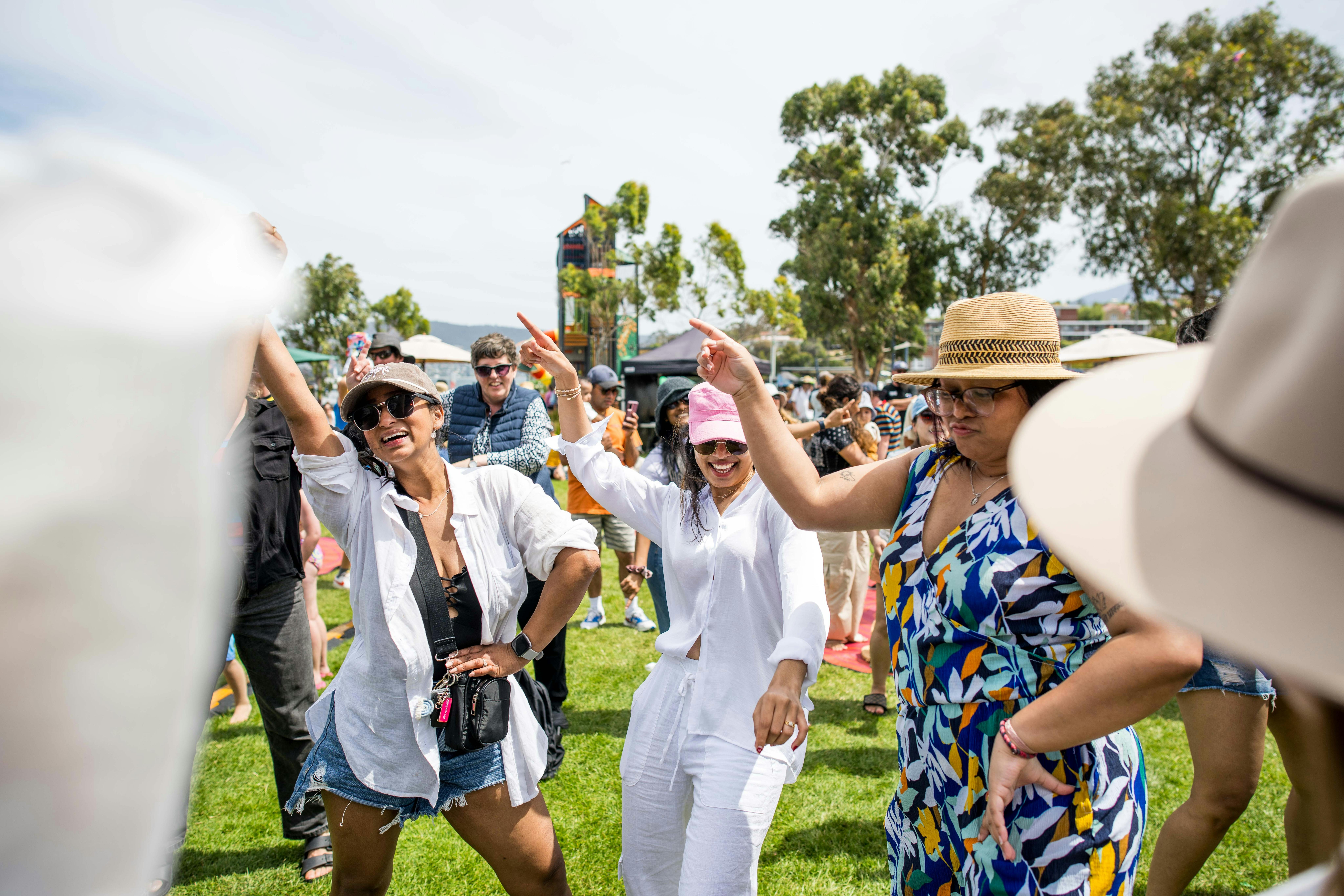 People smile and dance at an outdoor event.