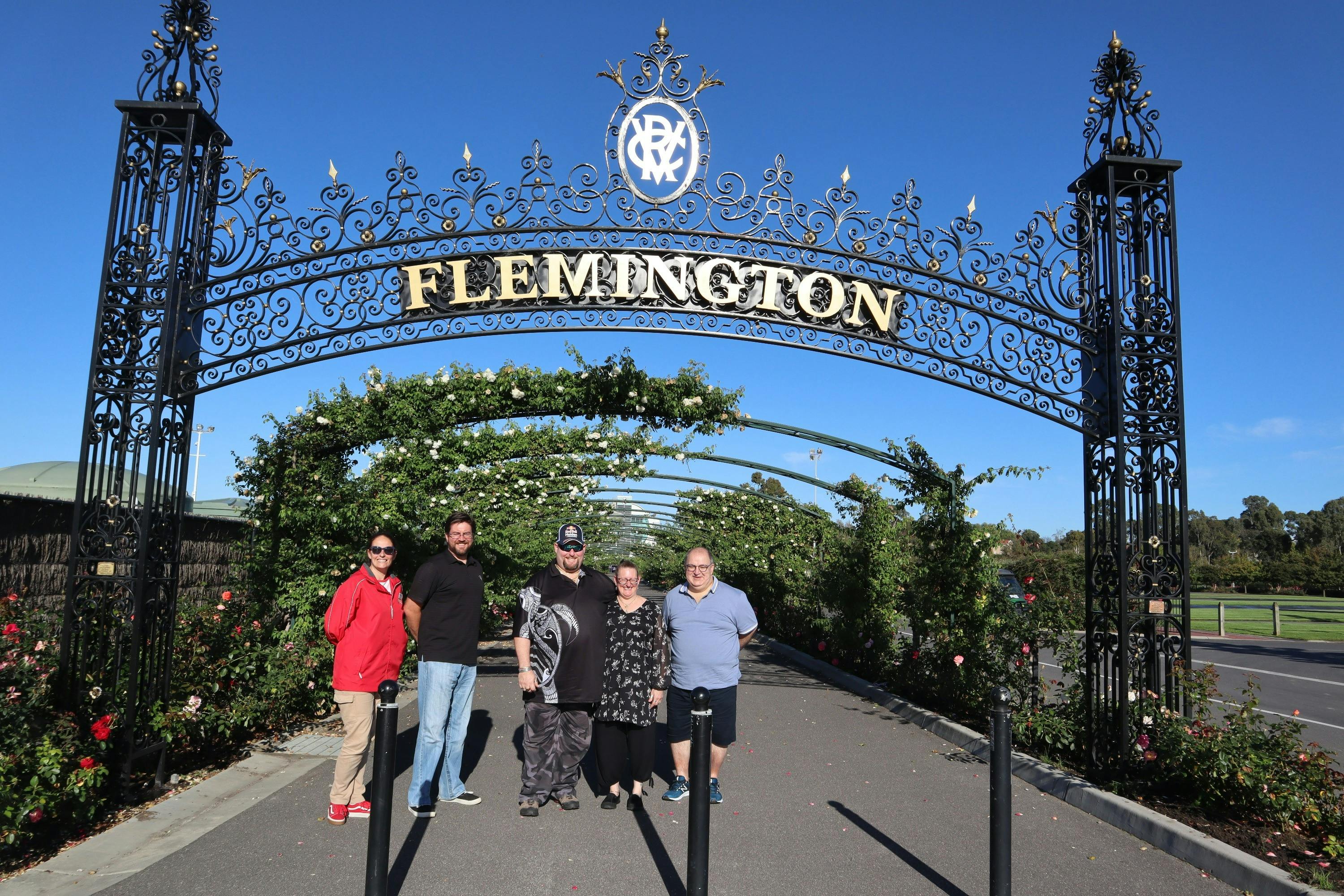 Tour host and guests standing under an arch with Flemington signage