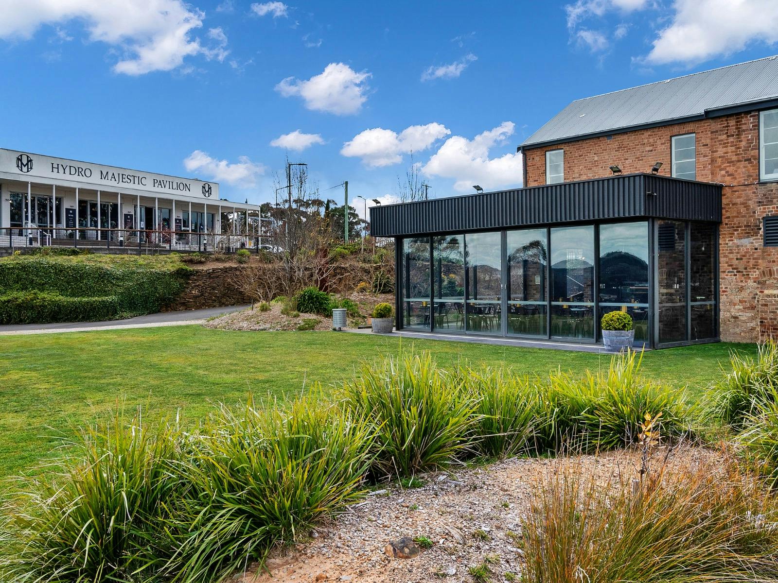 Grassy entrance with a gravel path, large modern glass panes of the Hydro Majestic and Boiler House