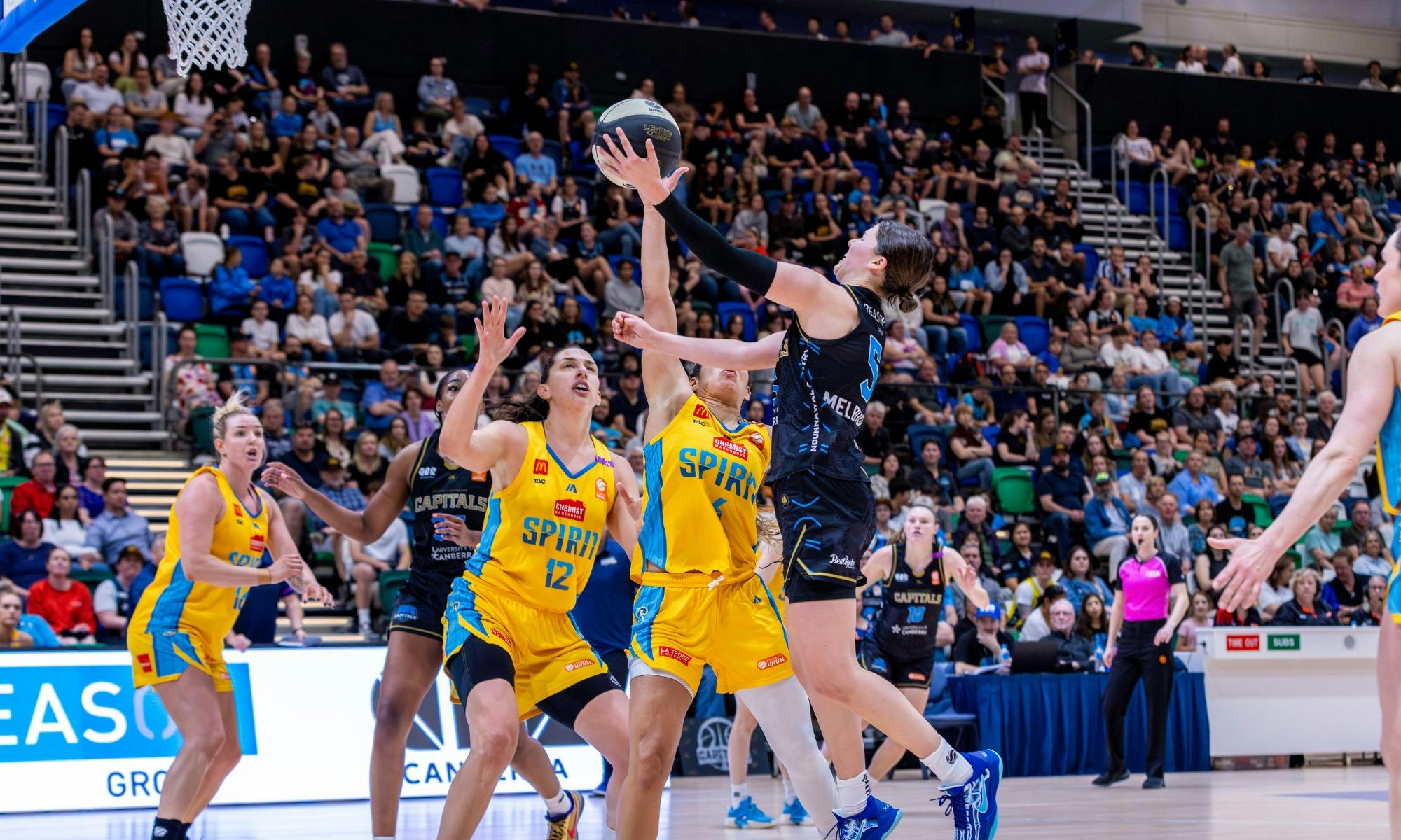 UC Capitals player driving to the basket for a layup during a WNBL game.