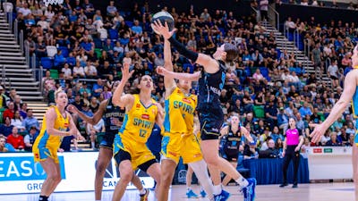 UC Capitals player driving to the basket for a layup during a WNBL game.